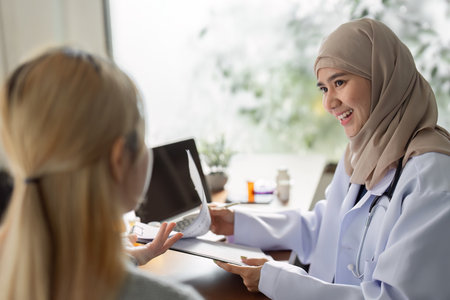 Friendly Muslim female doctor consulting with a patient in a modern healthcare setting, promoting diversity and inclusivity.の写真素材