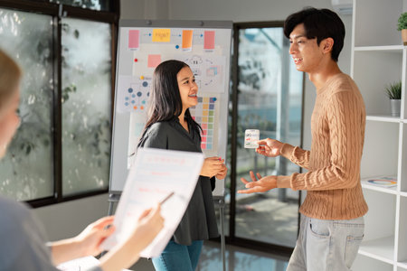 UX UI designer presenting ideas to a client with visuals in a bright office.
