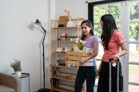 LGBTQ couple carrying a crate of flowers and essentials into their new home, symbolizing love and new beginnings.の写真素材