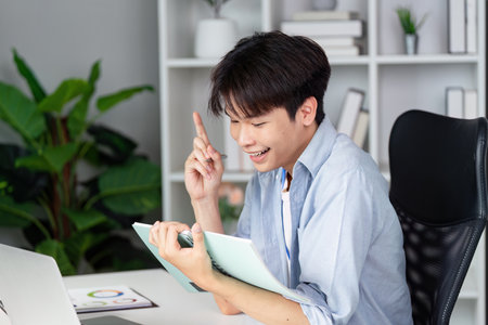 Engaged young man brainstorming ideas with a tablet in a bright office environment.の写真素材