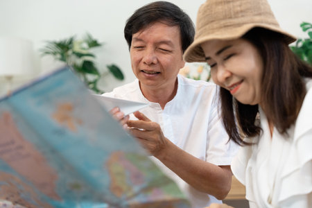 Couple reviewing travel plans and packing clothes together, enjoying the moment in their living...