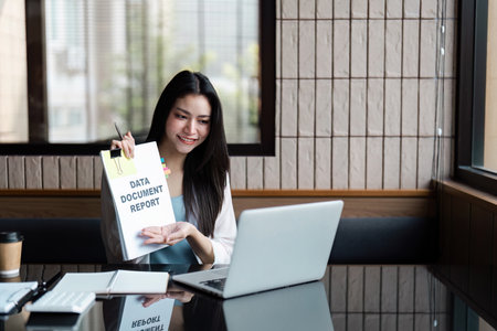Smiling businesswoman presenting a data report on a laptop, showcasing professionalism and...
