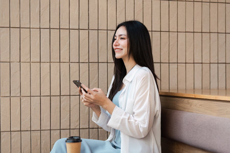 Professional woman using smartphone in a modern workspace, smiling and engaged.