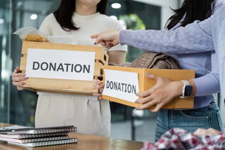 Volunteers holding donation boxes at a community event, collecting food and clothing for those in need.の写真素材