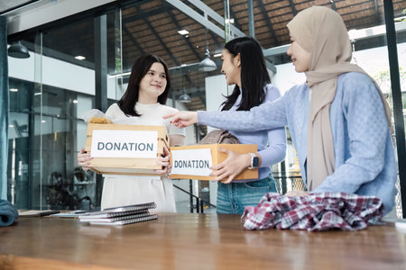 Diverse women sharing donation boxes and collaborating on community service project.の写真素材