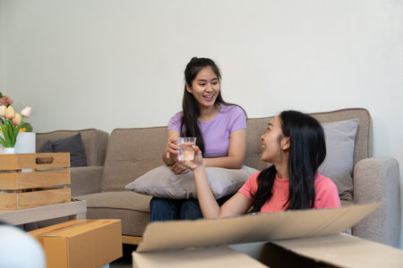 Cheerful friends enjoying a cozy indoor moment, sharing drinks while sitting on a sofa