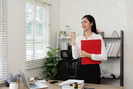 Happy accountant celebrating success in a modern office environment.の写真素材