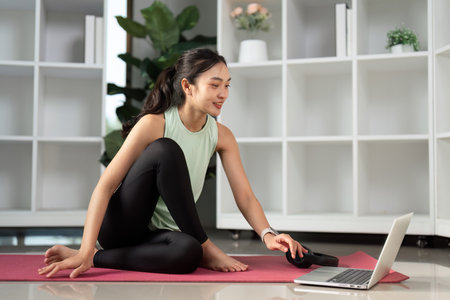 Young woman engaging in a virtual workout session on a laptop, promoting wellness.