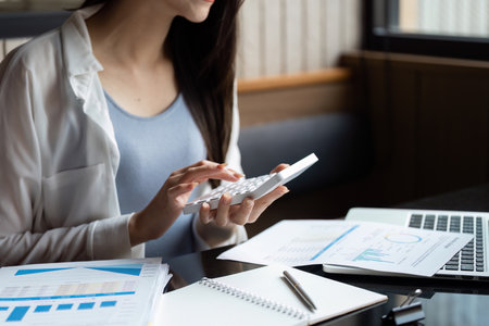 Financial analyst calculating budget using a calculator, reviewing financial documents.の写真素材