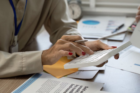 Accountant calculating financial figures with a calculator and reviewing reports