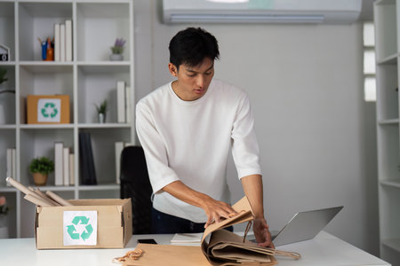 Young man organizing recyclable paper materials for eco-friendly practicesの写真素材