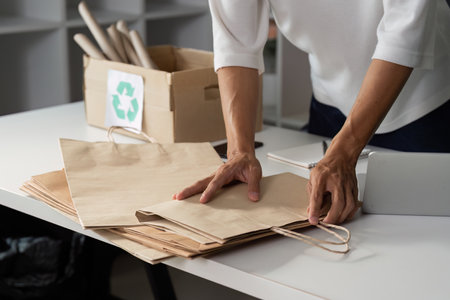 Individual organizing paper bags for recycling, promoting sustainable practices in daily life.の写真素材