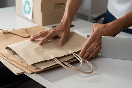 Person sorting and preparing paper bags for recycling, highlighting sustainable practices.