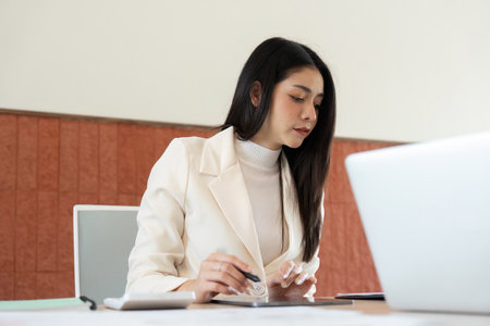 Businesswoman analyzing financial data on a laptop in a modern officeの写真素材