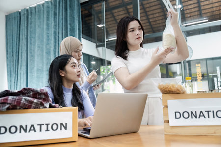 Diverse women discussing donation items while organizing contributions for community service.の写真素材