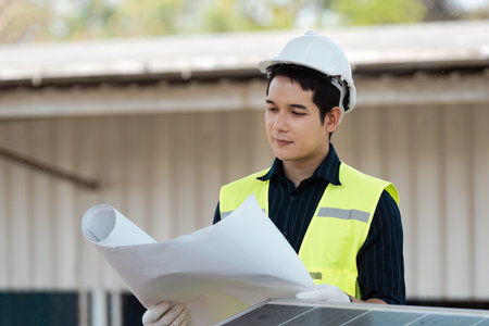 Focused engineer examining project blueprints. Professional assessing plans for sustainable energy solutions.の写真素材