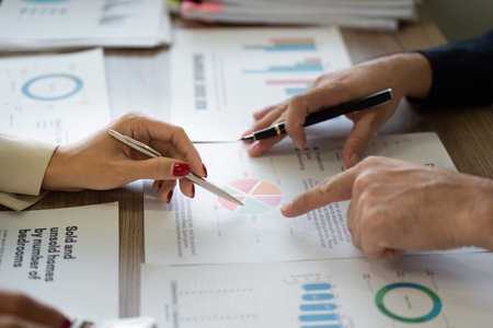 Collaborative financial analysis with team members reviewing charts and reports.の写真素材