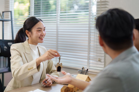 Real estate agent handing over keys to a new homeowner, showcasing professionalism and excitement.の写真素材