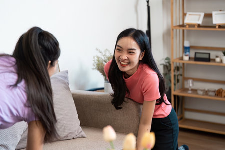 LGBTQIA couple sharing a joyful moment while moving furniture in their stylish living room.の写真素材