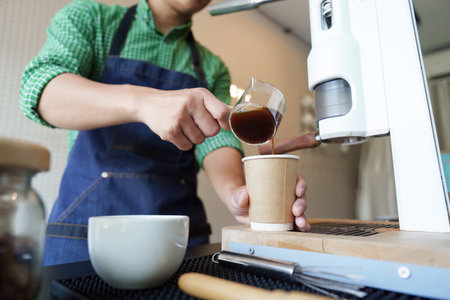 Sustainable Brewing Techniques and Artisanal Quality. A barista pours freshly brewed coffee into a cup, promoting sustainable coffee practices.の写真素材