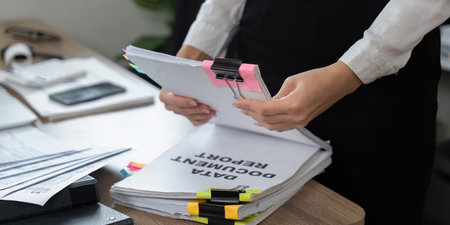 Detail-oriented professional sorting documents with binder clips and notesの写真素材