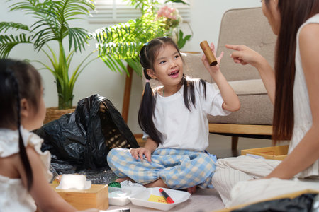 Inspiring Youth to Go Green. A young girl cheerfully showcasing recycled materials while her mother...