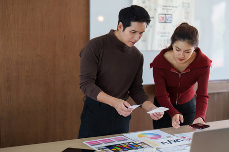 Planning and Design Review. Professionals analyzing design concepts on a conference table in an office setting.の写真素材