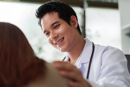 Patient Interaction and Comfort. A doctor smiles at a patient during a consultation.の写真素材