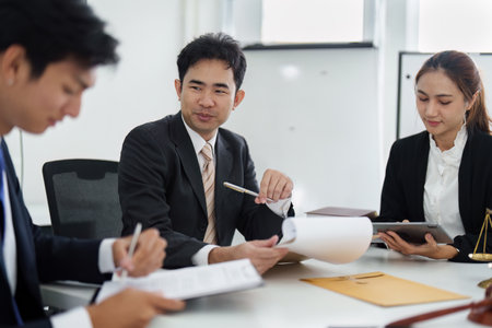 Law Firm Collaboration and Client Engagement. A group of lawyers engages in discussions while reviewing case documents and strategies.の写真素材