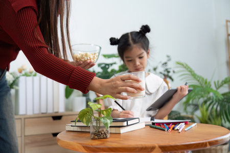 Learning and Nurturing. A mother attends to her daughter while she works on her school tasks.の写真素材