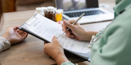 Patient Records and Healthcare Management. Doctor filling out medical records during consultation.の写真素材