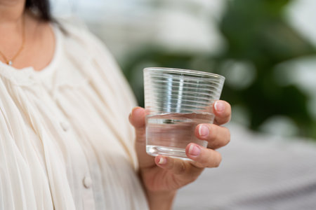 Hydration and Daily Health. An elderly woman drinking water for her health.の写真素材