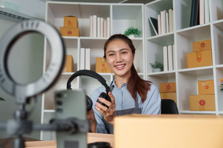 Entrepreneurship and Technology Use. A woman adjusts her headphones while preparing for an online meeting about her business.の写真素材