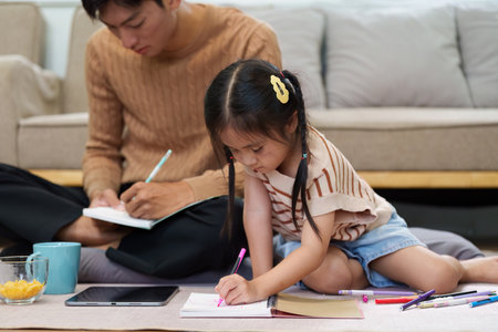 Learning and Family Bonding. A father and daughter engage in homework, fostering creativity and connection at home.の写真素材