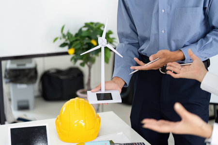 Innovation and Renewable Energy. An engineer showcasing a wind turbine model during a project discussion on sustainability.の写真素材