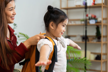 Getting Ready for School with a Backpack. A girl trying on her backpack with help from a supportive woman.の写真素材