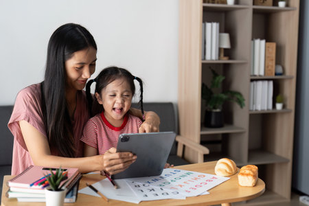 Digital Learning and Fun. A mother and daughter discover educational content on a tablet together.の写真素材