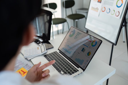 Business Presentation and Data Analysis. A professional presenting data insights on a laptop in a modern office setting.の写真素材