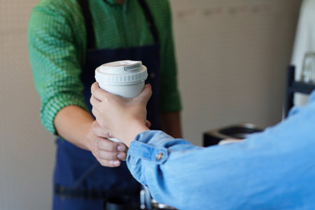 Sustainable Choices and Eco-Friendly Practices. A customer receiving a reusable coffee cup,...
