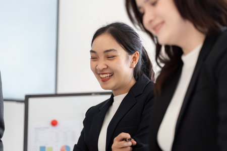 Teamwork and Positive Atmosphere. A businesswoman smiling and engaging with her colleagues in a meeting.の写真素材