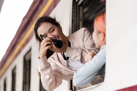 Capturing Moments and Joy. A young woman taking photos of her friend while enjoying their train journey.の写真素材