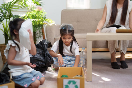 Learning and Play in Sustainability. Young children sort recyclables with their mother, practicing environmental responsibility.の写真素材