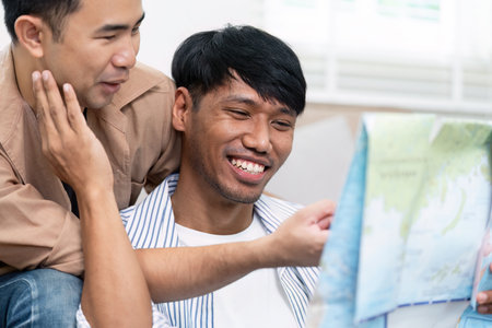 Couple Travel Enthusiasm. Two men joyfully planning their next travel destination with a map.