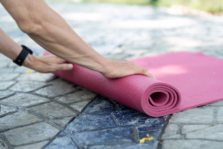 Wellness in Yoga: Senior preparing yoga mat outdoorsの写真素材