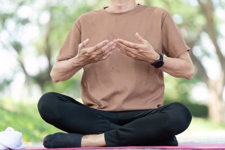 Wellness yoga practice with senior man meditating outdoorsの写真素材