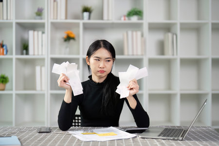 Frustrated young woman overwhelmed with receipts and financial paperworkの写真素材