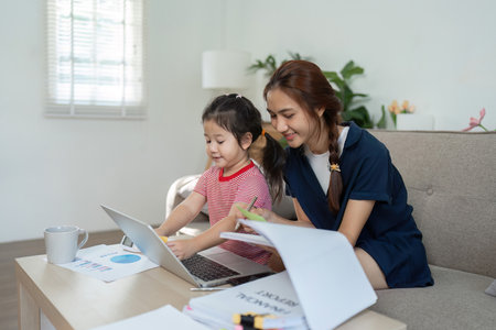 Mother and daughter collaborating on a project at home, emphasizing learning and togetherness.の写真素材