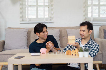 Couple excitedly presenting a wooden house model while planning real estate investment