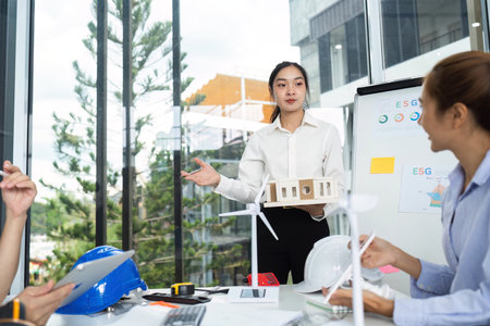 Sustainable Architecture Presentation. Female architect presenting eco-friendly model to team.の写真素材