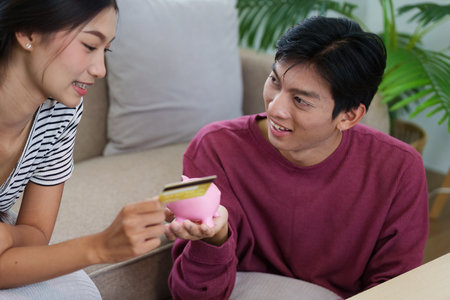 Savings and Spending. A couple learning about savings techniques while having fun with their pink piggy bank.の写真素材